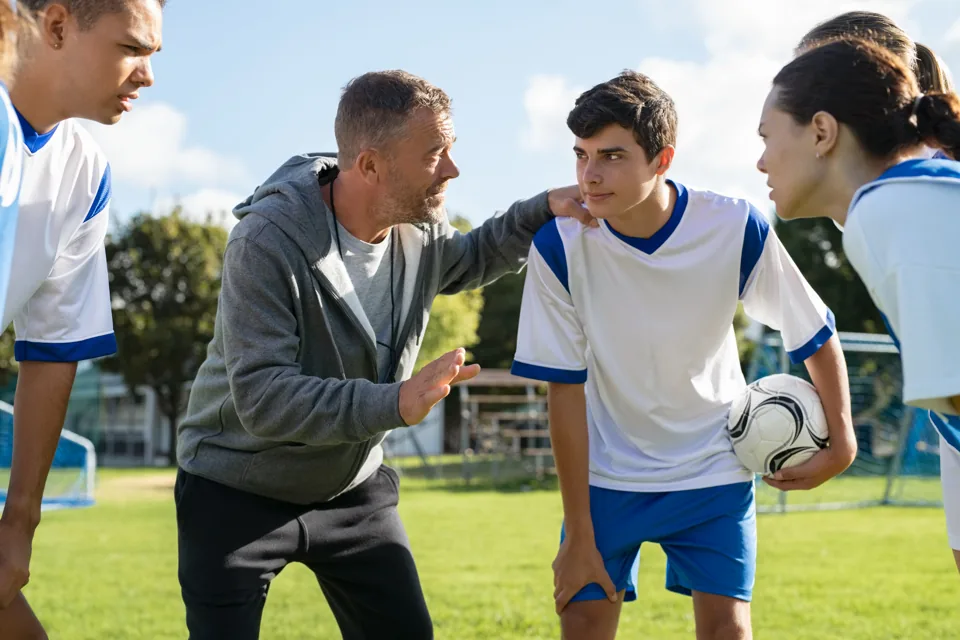A football coach talking with players during a training session.
